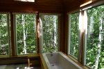 Soaking tub in en-suite Primary Bathroom with view of surrounding white birch trees
